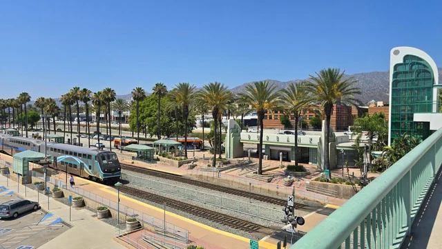 Metrolink train at Downtown Burbank station, with palm trees and mountains